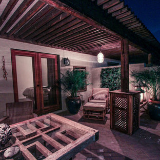 Ispirazione per un patio o portico boho chic di medie dimensioni e in cortile con pavimentazioni in mattoni e un tetto a sbalzo