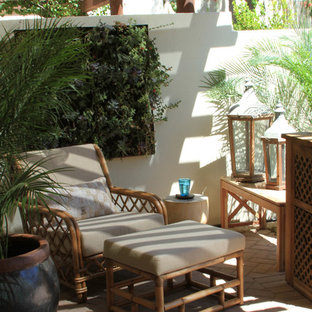 Esempio di un patio o portico boho chic di medie dimensioni e in cortile con pavimentazioni in mattoni e un tetto a sbalzo