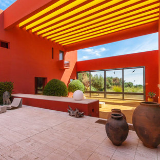 Imagen de patio contemporáneo con suelo de baldosas y pérgola