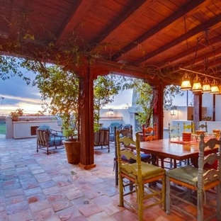 Ispirazione per un grande patio o portico mediterraneo dietro casa con un caminetto, piastrelle e un tetto a sbalzo
