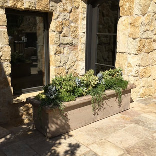 Foto di un patio o portico mediterraneo in cortile con un focolare, pavimentazioni in pietra naturale e nessuna copertura