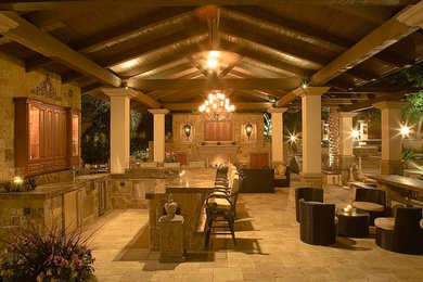 Patio kitchen - large mediterranean backyard stone patio kitchen idea in Los Angeles