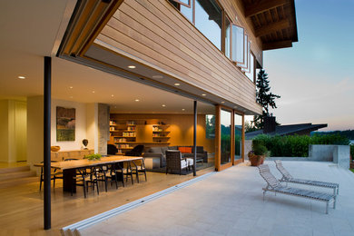 This is an example of a large contemporary back patio in Seattle with natural stone paving and a roof extension.