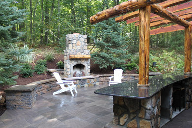 Modelo de patio clásico de tamaño medio en patio trasero con brasero, adoquines de piedra natural y pérgola