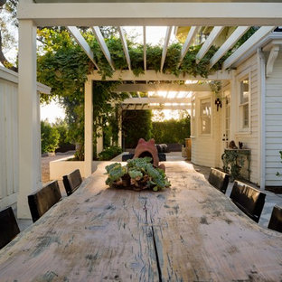 Idee per un ampio patio o portico country con un focolare, pavimentazioni in cemento e una pergola