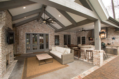 Example of a large classic backyard concrete patio kitchen design in Houston with a roof extension