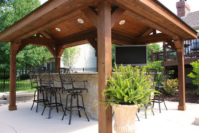 Diseño de patio clásico de tamaño medio en patio trasero con cocina exterior, losas de hormigón y pérgola