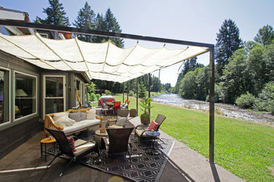 Example of a mid-sized arts and crafts backyard concrete paver patio design in Portland with an awning