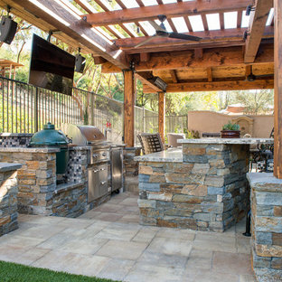 Patio kitchen - mid-sized transitional backyard stone patio kitchen idea in Orange County with a pergola