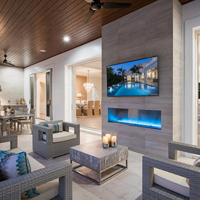 Example of a trendy backyard stone patio design in Miami with a roof extension and a fireplace