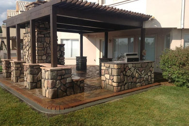 Réalisation d'une terrasse arrière tradition de taille moyenne avec une cuisine d'été, des pavés en brique et une pergola.