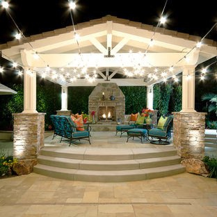 Immagine di un grande patio o portico stile marino dietro casa con un focolare, pavimentazioni in pietra naturale e una pergola
