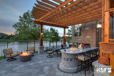Example of a huge mountain style backyard brick patio kitchen design in Chicago with a pergola