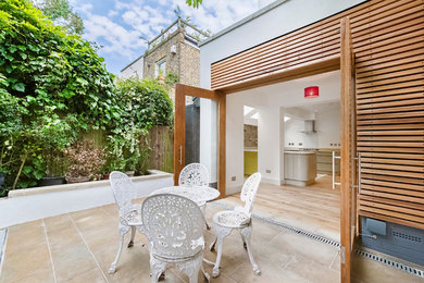 Inspiration for a medium sized contemporary back patio in London with natural stone paving and an outdoor kitchen.
