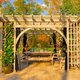 Exemple d'une très grande terrasse arrière chic avec une pergola et des pavés en pierre naturelle.