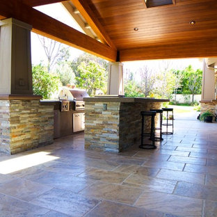 Idee per un grande patio o portico stile americano dietro casa con piastrelle e un tetto a sbalzo