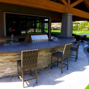 Ispirazione per un grande patio o portico stile americano dietro casa con piastrelle e un tetto a sbalzo