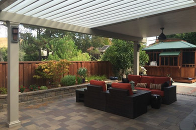 Ejemplo de patio de estilo americano de tamaño medio en patio trasero con suelo de baldosas y pérgola