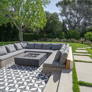 Immagine di un grande patio o portico design dietro casa con un focolare, piastrelle e nessuna copertura