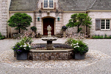 Foto de patio tradicional con fuente y gravilla