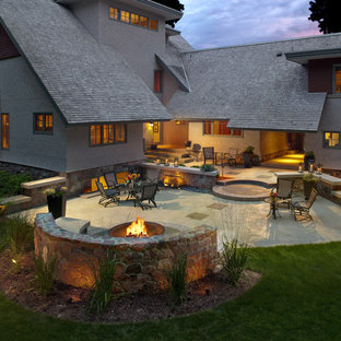 Immagine di un grande patio o portico stile americano dietro casa con un focolare e lastre di cemento