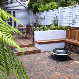 Immagine di un patio o portico minimal con pavimentazioni in mattoni e un focolare