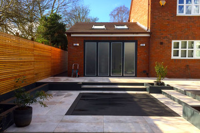 This is an example of a contemporary back patio in West Midlands with tiled flooring.