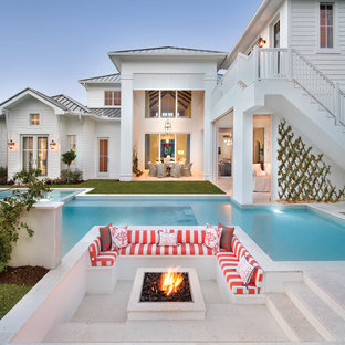 Idee per un ampio patio o portico stile marino dietro casa con un focolare