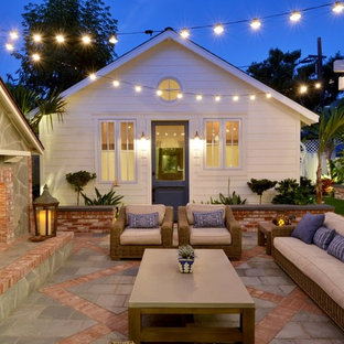 Idee per un piccolo patio o portico costiero dietro casa con un focolare, piastrelle e nessuna copertura