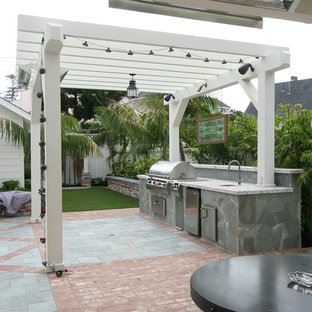 Example of a mid-sized eclectic backyard brick patio kitchen design in San Diego with a pergola