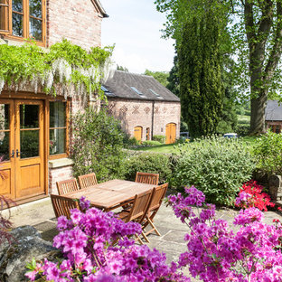 Ispirazione per un patio o portico country dietro casa con pavimentazioni in pietra naturale e nessuna copertura