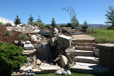 Mid-sized elegant backyard stone patio photo in Other with no cover