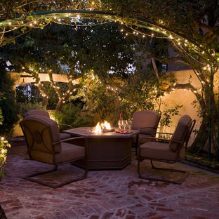 Esempio di un patio o portico tradizionale di medie dimensioni e in cortile con un focolare, pavimentazioni in mattoni e nessuna copertura
