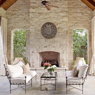 Idee per un patio o portico dietro casa con pavimentazioni in pietra naturale, un tetto a sbalzo e un caminetto