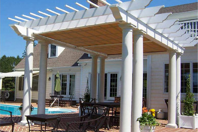 Diseño de patio clásico grande en patio trasero con adoquines de ladrillo y pérgola