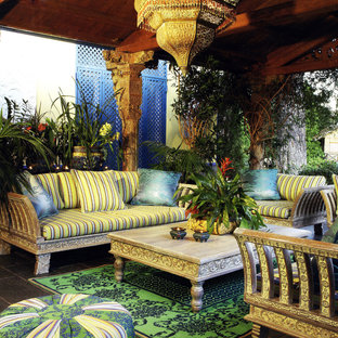 Idee per un patio o portico tropicale di medie dimensioni e dietro casa con piastrelle e un tetto a sbalzo