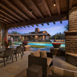 Patio - large southwestern backyard patio idea in Phoenix with a fire pit and a roof extension