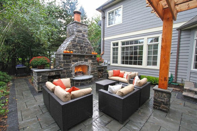 Modelo de patio clásico grande en patio trasero con cocina exterior, suelo de hormigón estampado y pérgola
