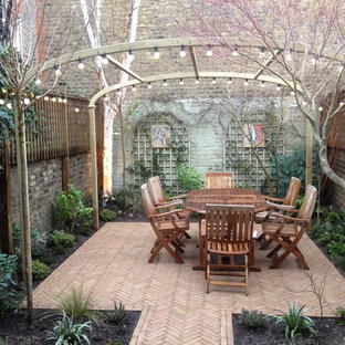 Ispirazione per un patio o portico chic di medie dimensioni e dietro casa con pavimentazioni in mattoni