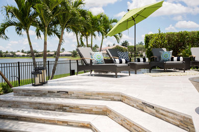 Mid-sized island style backyard stone patio photo in Miami with a fire pit and no cover