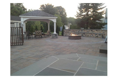 Large elegant backyard concrete paver patio photo in New York with a fire pit and a gazebo