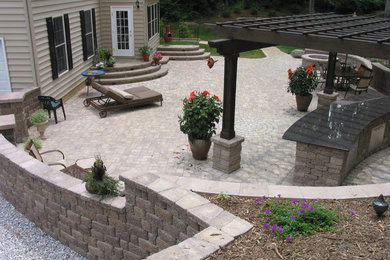 Inspiration for a large timeless backyard concrete paver patio kitchen remodel in Baltimore with a pergola