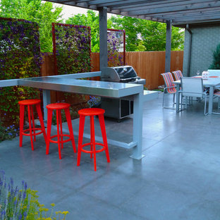 Immagine di un patio o portico moderno dietro casa con cemento stampato e una pergola