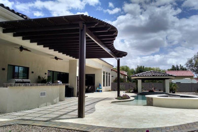 Patio - mediterranean backyard concrete paver patio idea in Phoenix with a pergola
