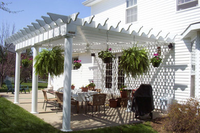 Foto de patio clásico de tamaño medio en patio trasero con losas de hormigón y pérgola