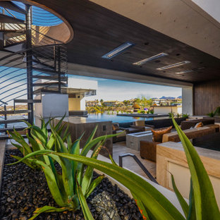 Idee per un grande patio o portico contemporaneo dietro casa con un focolare e un tetto a sbalzo