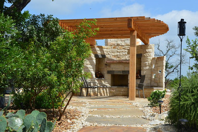 Modelo de patio actual grande en patio trasero con brasero, adoquines de piedra natural y pérgola
