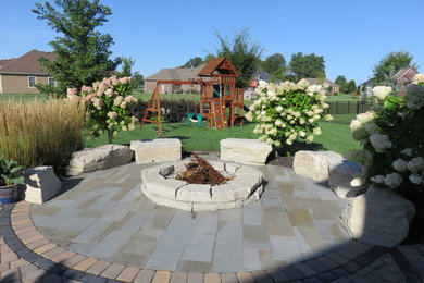 Patio - large traditional backyard brick patio idea in Other with a fire pit and no cover