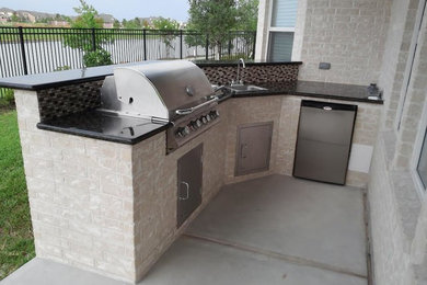 Inspiration for a small transitional backyard concrete patio kitchen remodel in Houston with a roof extension