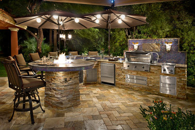 Patio kitchen - large mediterranean backyard concrete paver patio kitchen idea in Las Vegas with an awning